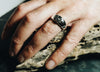 Mans hand wearing masculine silver ring with Emerald shape stone made from cremation ashes