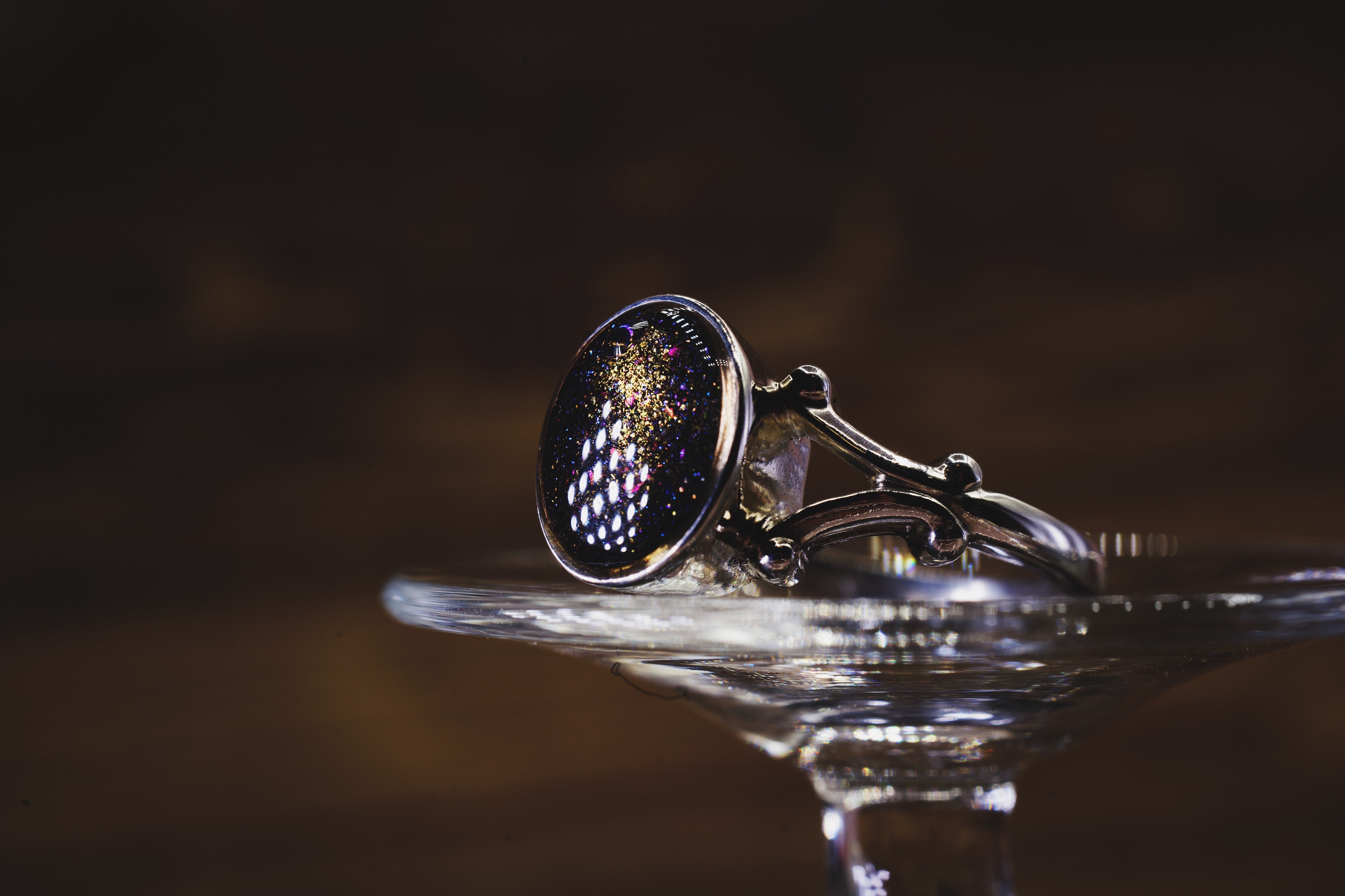 Silver ring with a dark purple cremation ash gemstone on a reflective surface