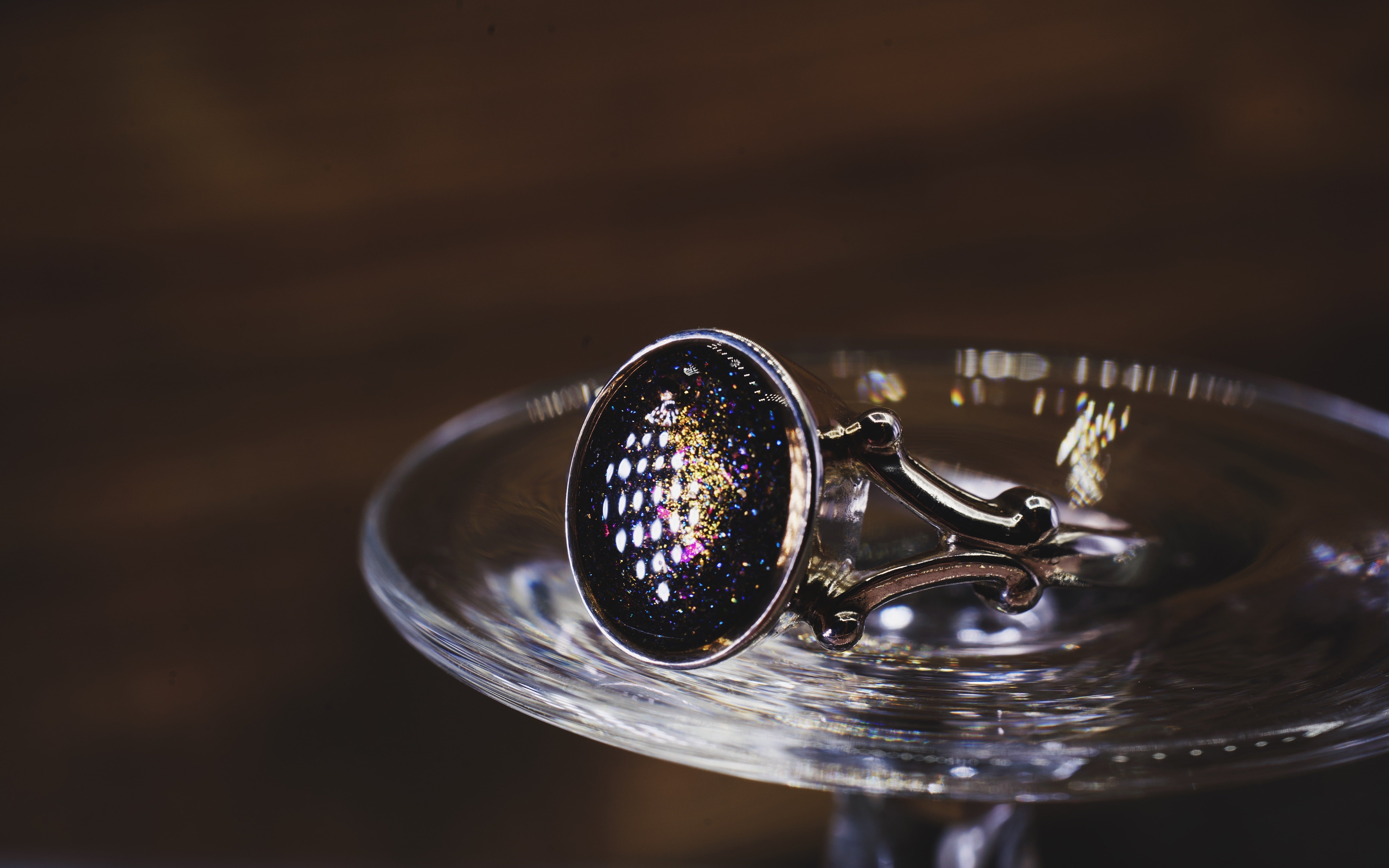 Silver ring with a dark purple cremation ash gemstone on a reflective surface