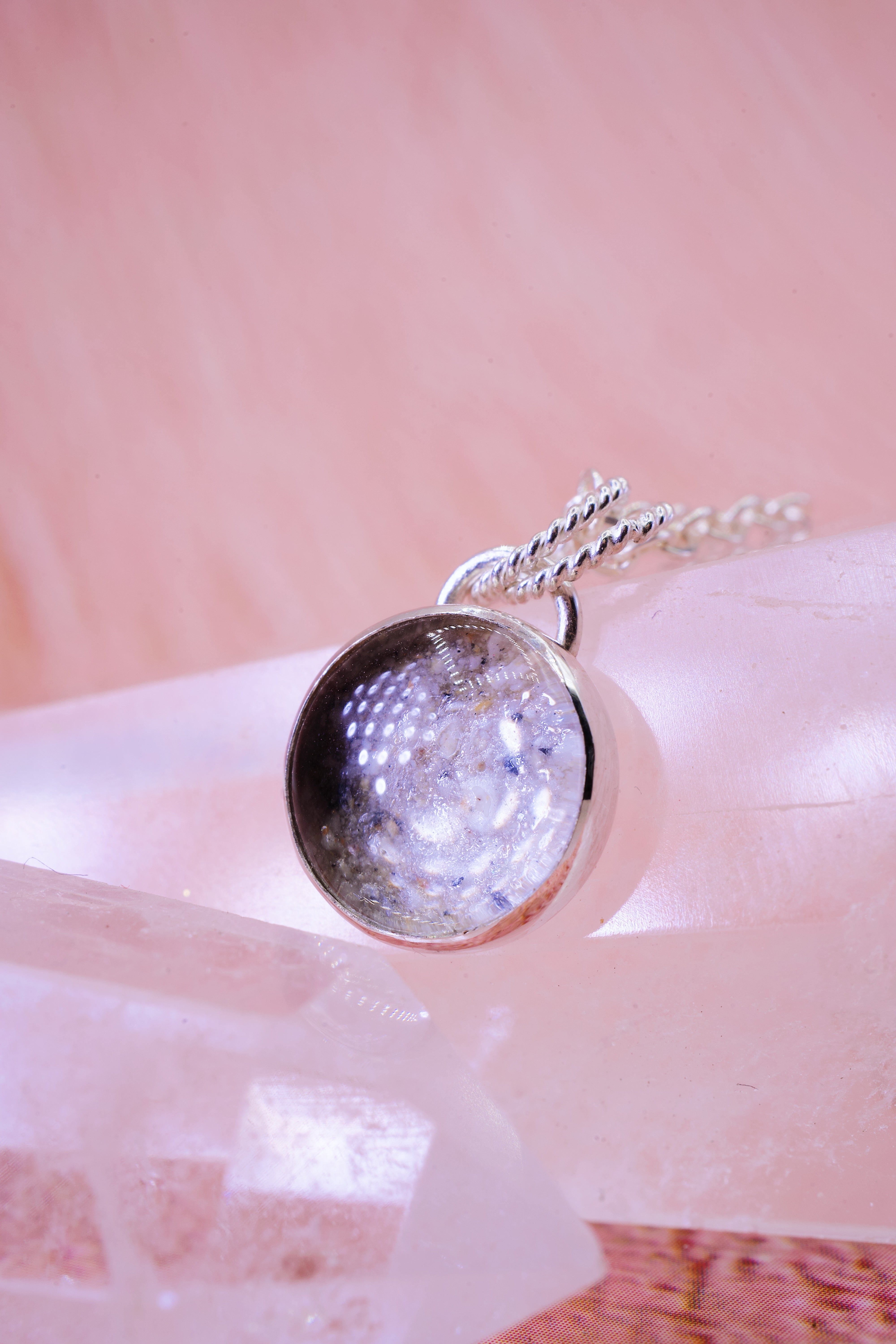 silver round pendant with ashes and clear glass on top