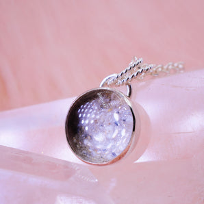 silver round pendant with ashes and clear glass on top